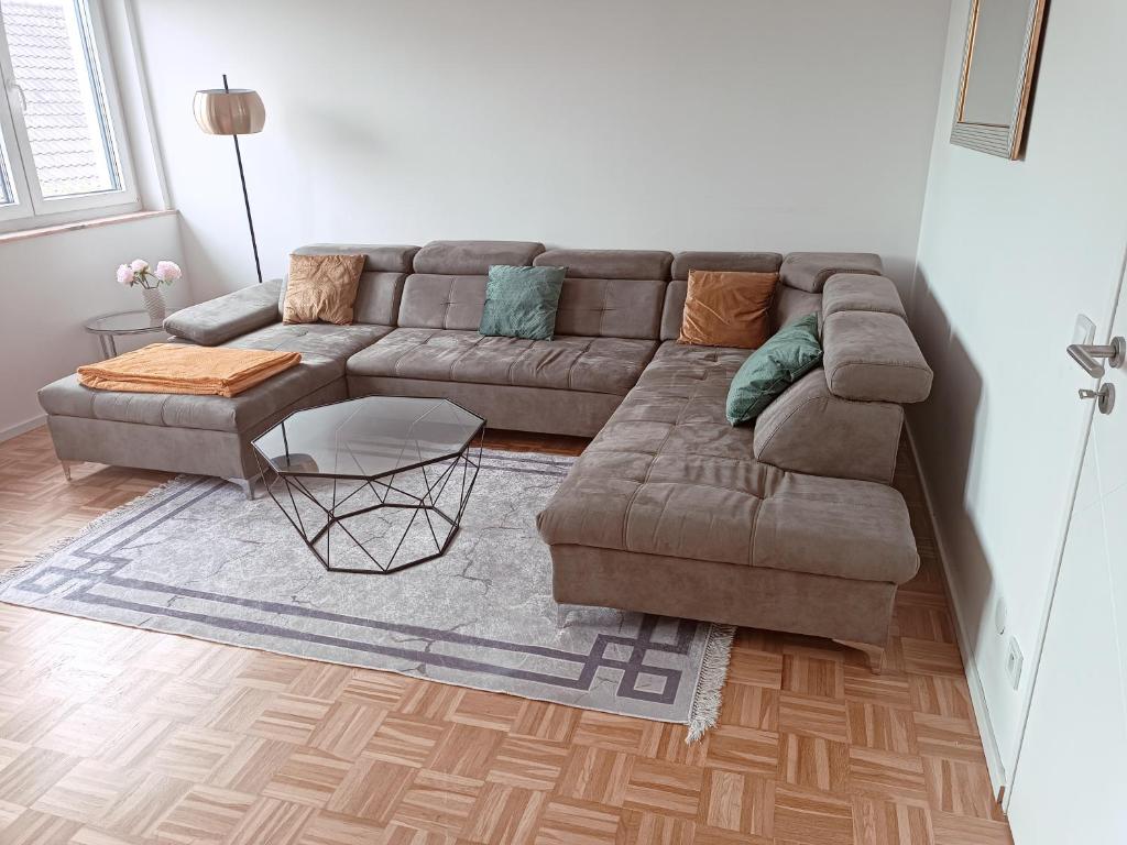 ein Wohnzimmer mit einem braunen Sofa und einem Tisch in der Unterkunft Vaste appartement cosy avec parking gratuit et espace de travail in Illkirch-Graffenstaden