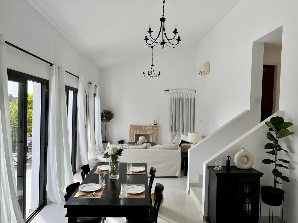 ein weißes Wohnzimmer mit einem Tisch und einem Sofa in der Unterkunft Zeus Holiday Home in Pissouri