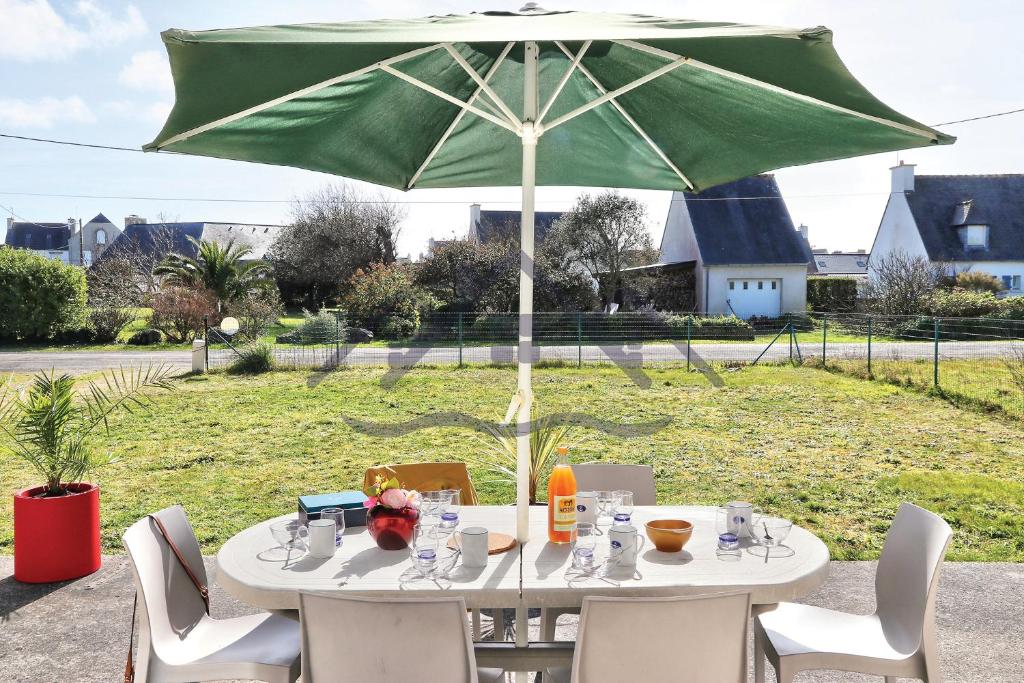 a table with a green umbrella on a patio at LocaLise - M12 - La petite Ty Marjan - Maison familiale avec jardin - A quelques pas des plages et du centre - Animaux admis - Wifi inclus - Draps inclus in Le Guilvinec