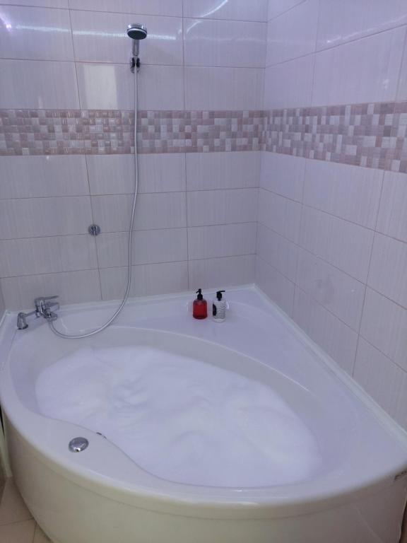 a bath tub with a shower with two bottles on it at Love Holiday Suite 2 in Tris Elies