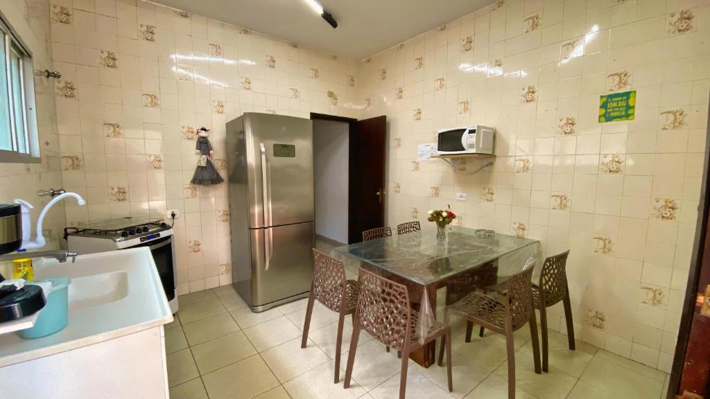 a kitchen with a table with chairs and a refrigerator at Casa uma Quadra da Praia das Asturias com área gourmet in Guarujá