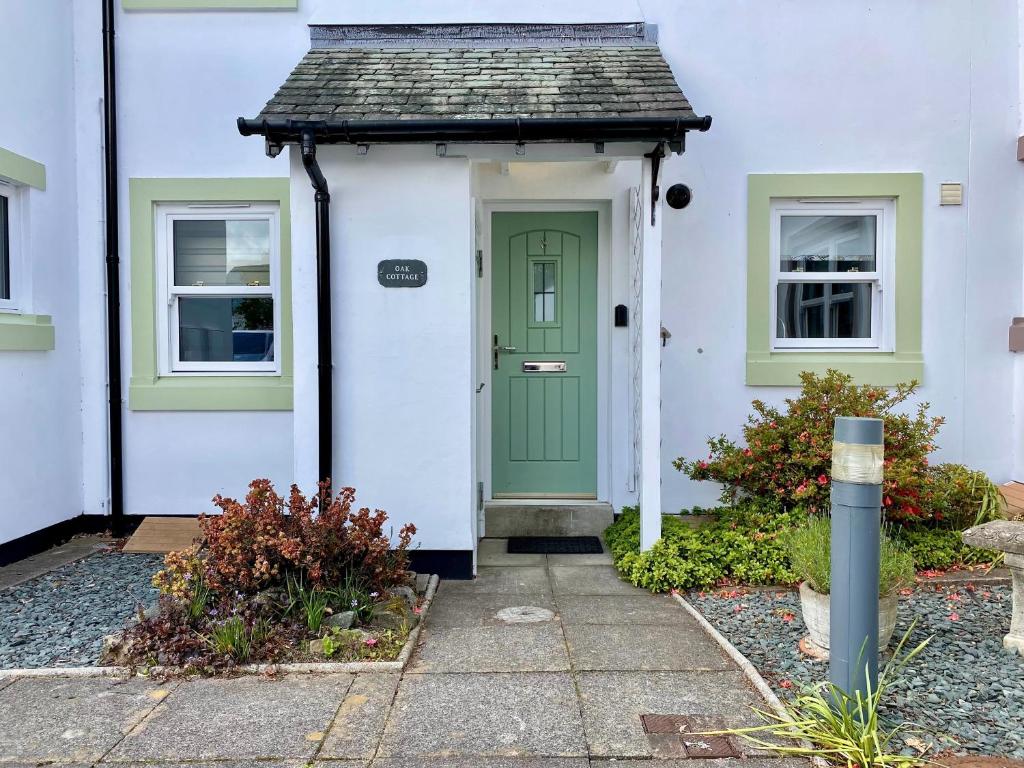 a white house with a green door and windows at 8 Howrahs Court, Keswick in Keswick
