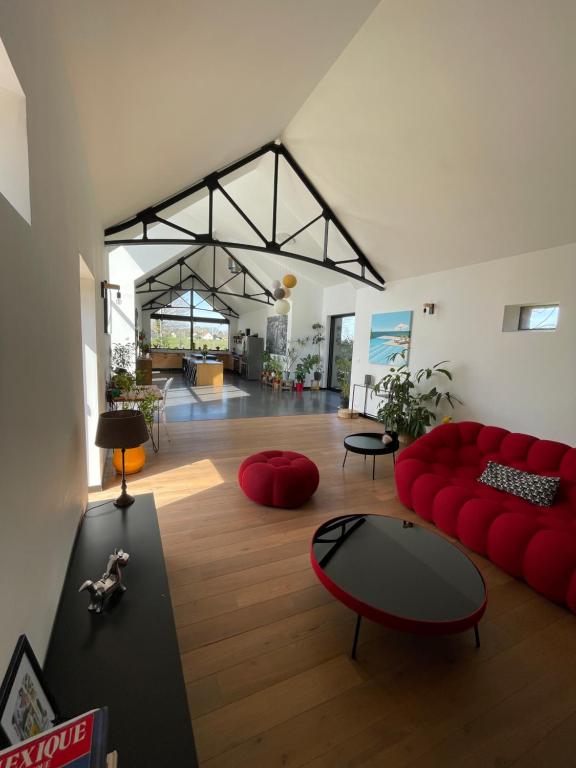 uma sala de estar com um sofá vermelho e uma mesa em Chambres privées dans fermette rénovée proche du Mans au calme em Changé