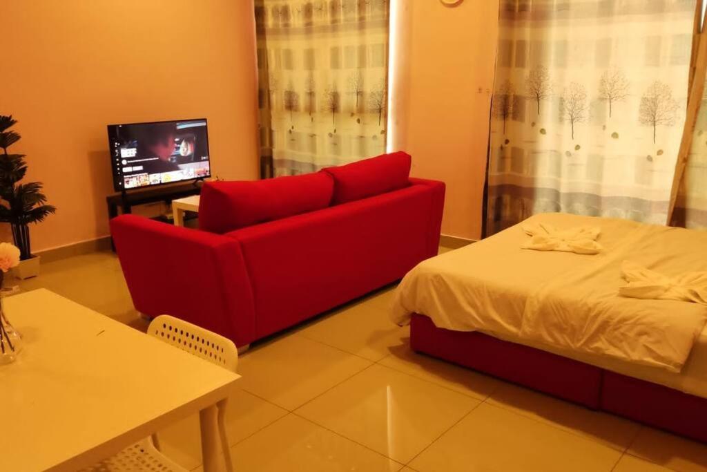 a living room with a red couch and a bed at CQ1305-Selfcheckin-Netflix-Wifi-Parking-Cyberjaya, Cybersquare Soho,2012 in Cyberjaya