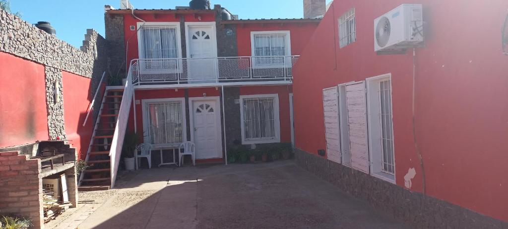 a red building with white doors and a balcony at Cuty Nakey in Puerto Madryn