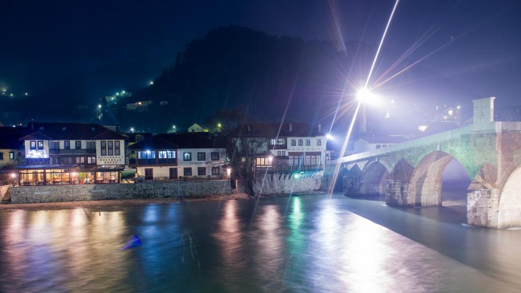 un puente sobre un río con edificios por la noche en Hotel Konak Konjic, en Konjic