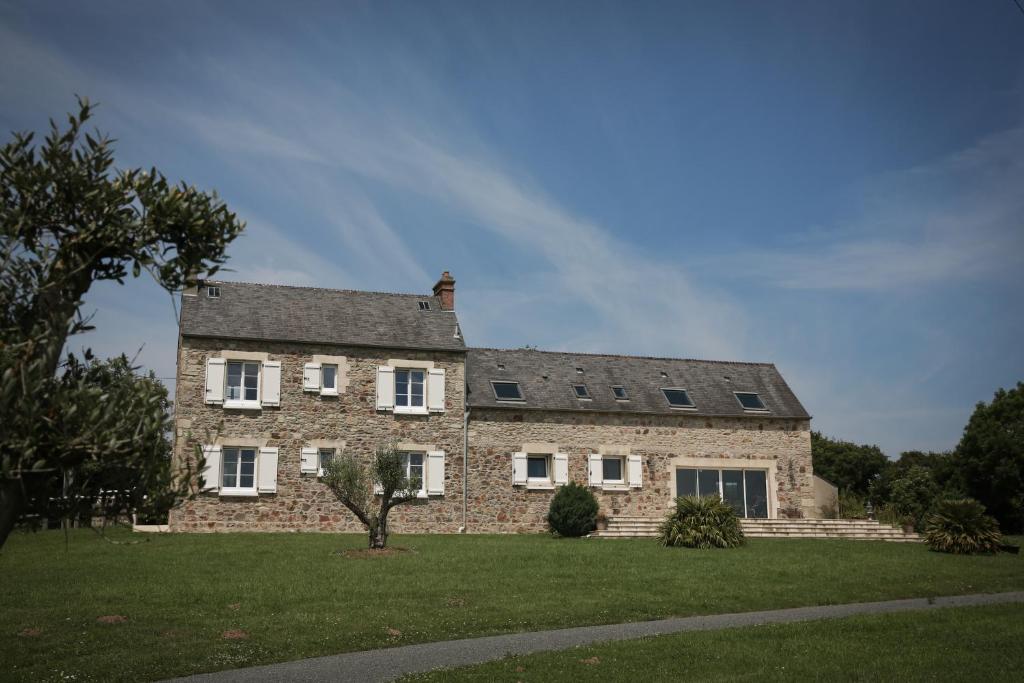 une grande maison en briques avec un toit gris dans l'établissement CRASVILLE- EN COTENTIN VUE EPOUSTOUFLANTE SUR LA MER, à Crasville