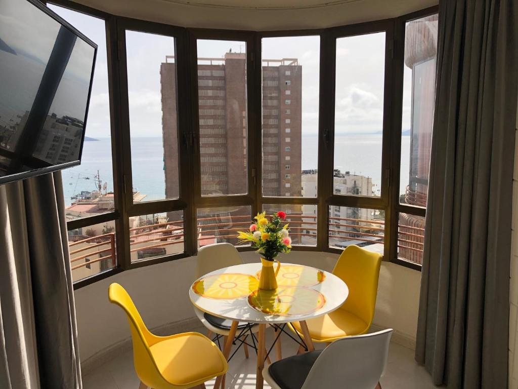 une table et des chaises dans une pièce avec des fenêtres dans l'établissement Milan Soria Luxury Coblanca XII, à Benidorm