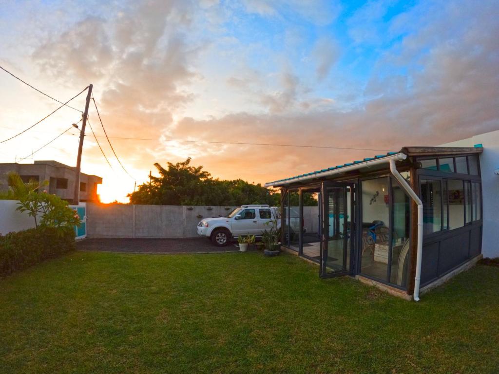 a small greenhouse in a yard with the sunset in the background at Cozy house for Kite & windsurfers (Le Morne) in Le Morne