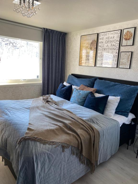 sypialnia z dużym łóżkiem z niebieską pościelą i oknem w obiekcie Hundbergan apartment-free parking-15 min from Tromsø w mieście Trondalen