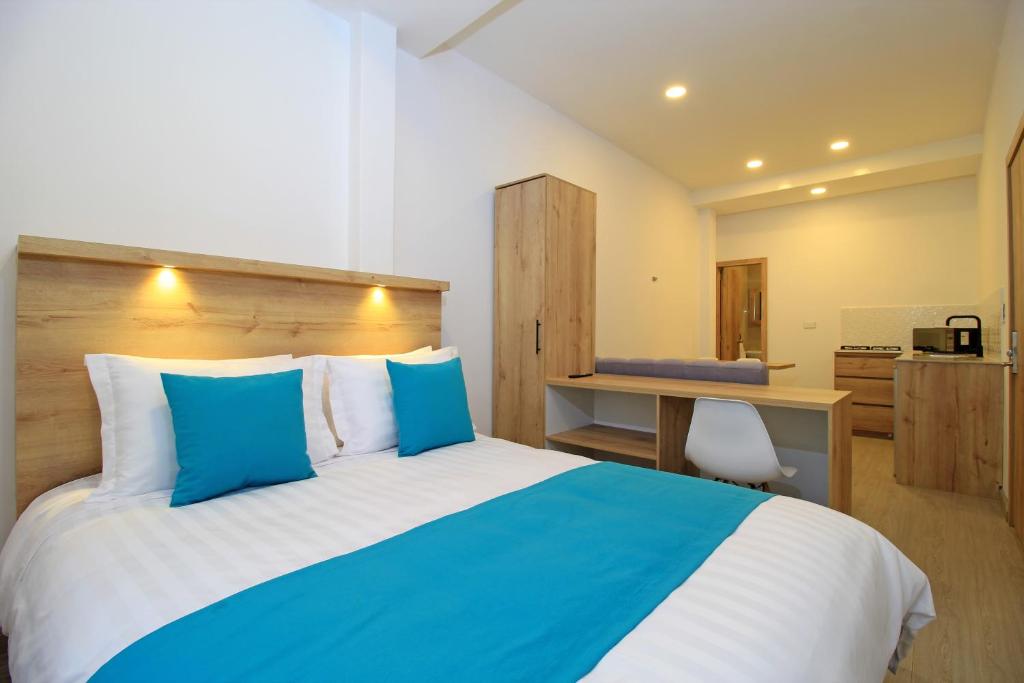 a bedroom with a bed with blue pillows and a desk at APART HOTEL CASA BLANCA in Cuenca