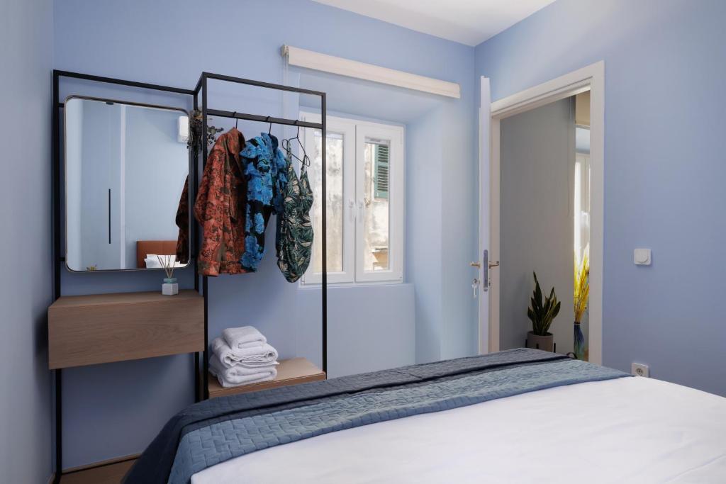 um quarto com uma cama com paredes azuis e um espelho em Old Town Hall Apartment em Corfu Town