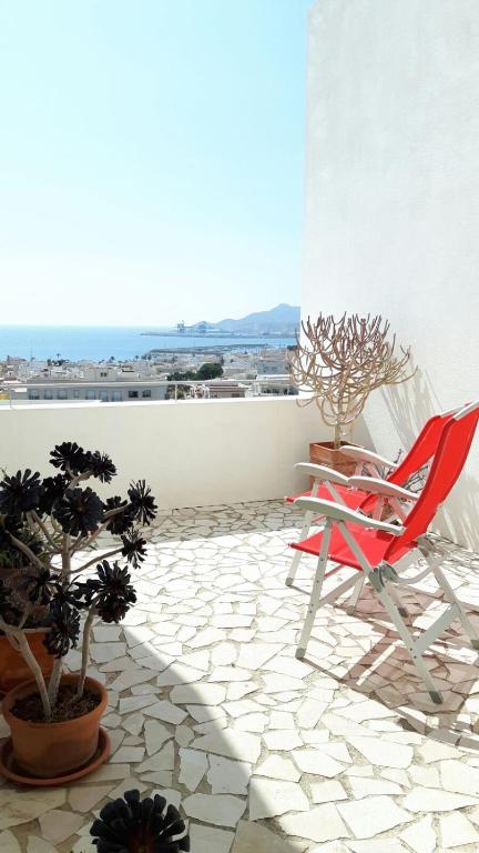 a patio with a red chair and potted plants at APARTAMENTO TURÍSTICO CARBONERAS in Carboneras