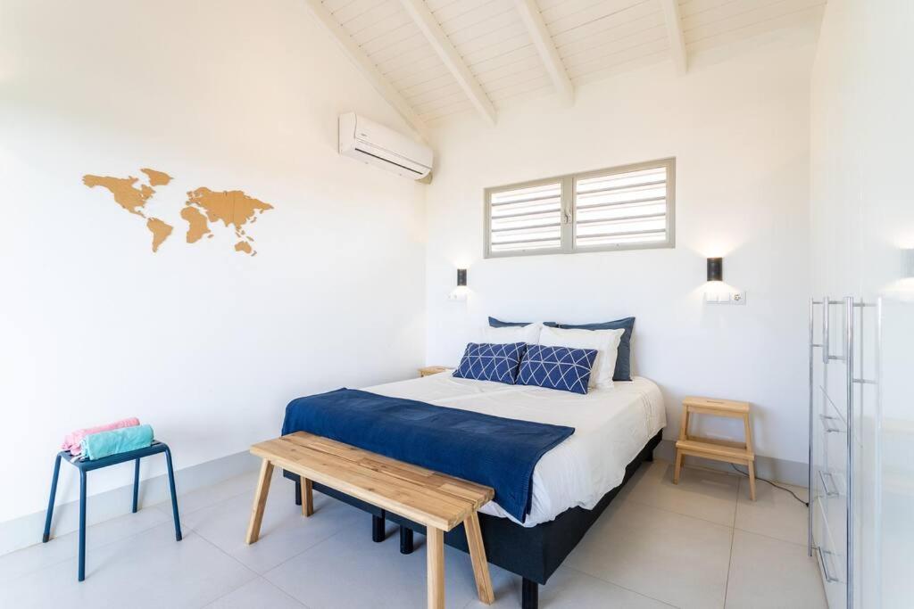 Dormitorio blanco con cama y mesa de madera en Stylish Apartment with Swimming Pool, en Kralendijk
