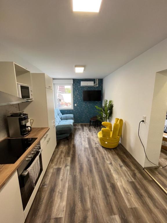 a kitchen with white cabinets and a yellow chair in a room at Sam Apartments LU/Oppau in Ludwigshafen am Rhein