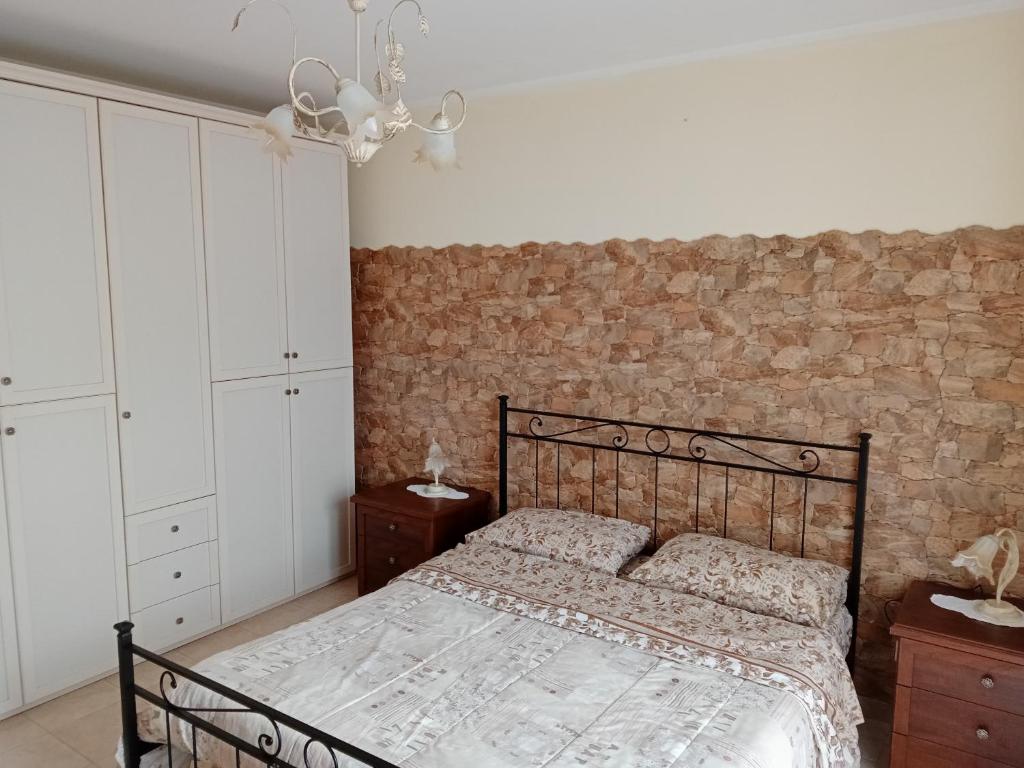 1 dormitorio con cama y pared de ladrillo en Belvedere Apartment en SantʼAlfio