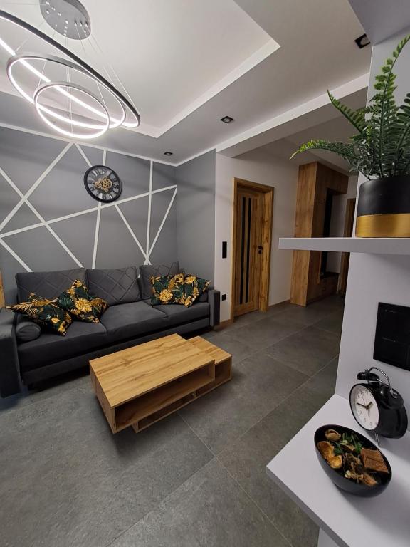 een woonkamer met een zwarte bank en een houten salontafel bij Apartament NATA in Zakopane