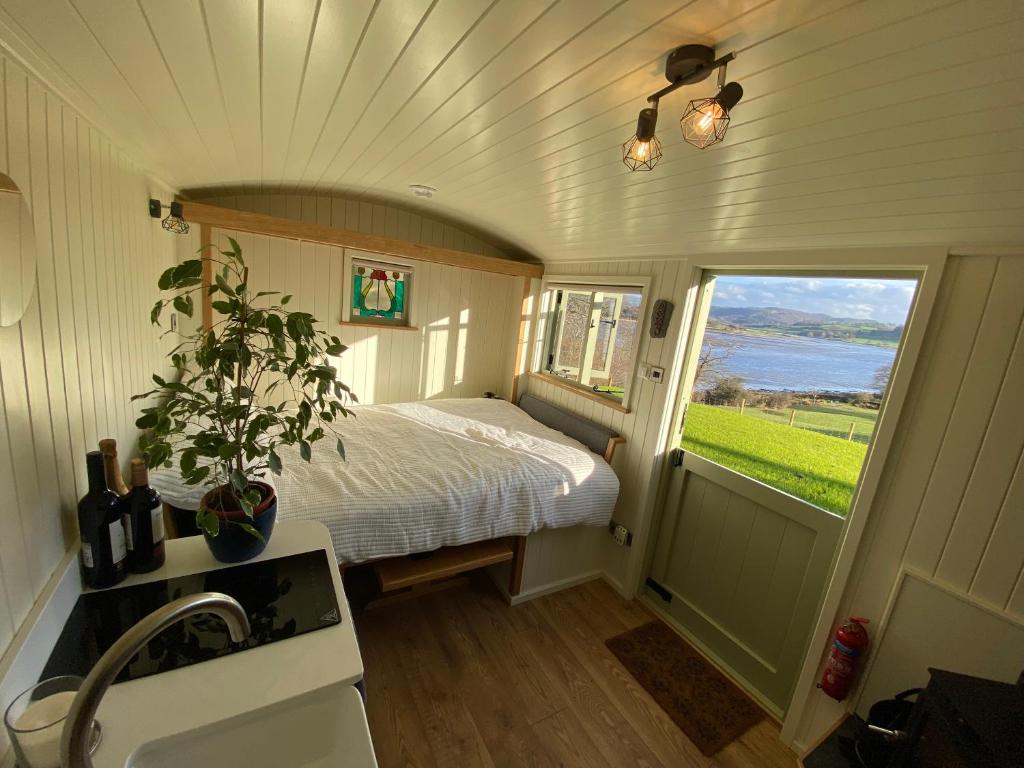 a small bedroom with a bed and a window at Shepherds Hut, Conwy Valley in Conwy