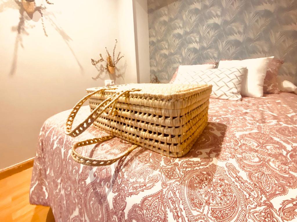 ein Korbkorb auf einem Bett in der Unterkunft Apartamenro A Tixola casco histórico in Pontevedra