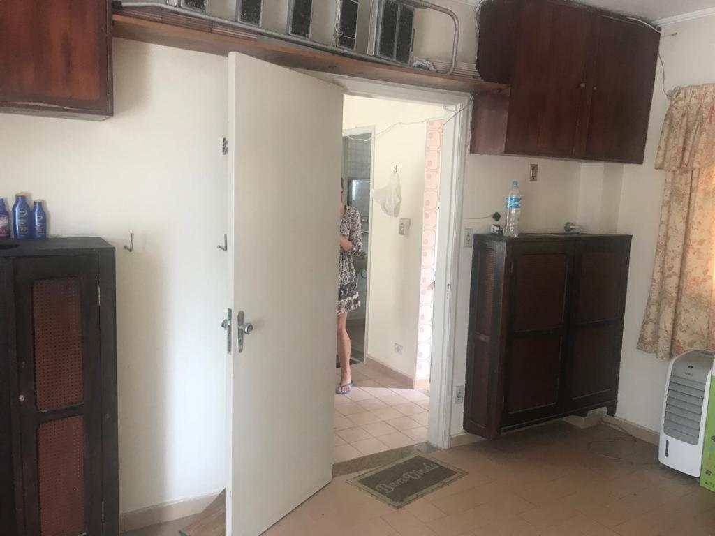 a woman standing in a kitchen looking into a room at Apartamento no edifício Abaeté in Mongaguá