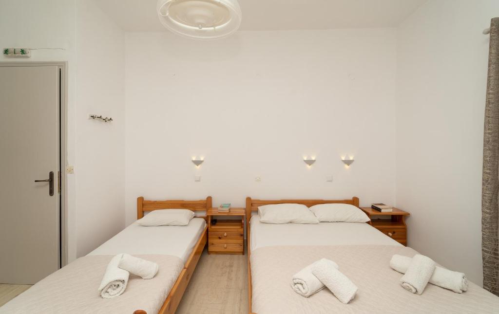 two beds in a room with white walls at Tsimiklis Apartments in Finikounta
