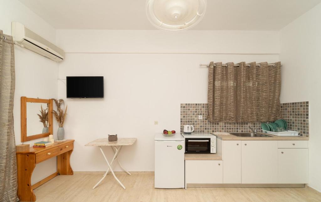 a kitchen with white cabinets and a microwave at Tsimiklis Apartments in Finikounta