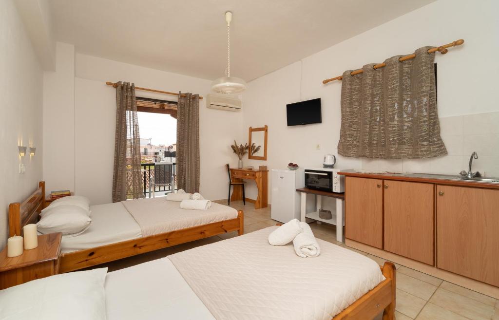 a bedroom with two beds and a kitchen with a sink at Tsimiklis Apartments in Finikounta