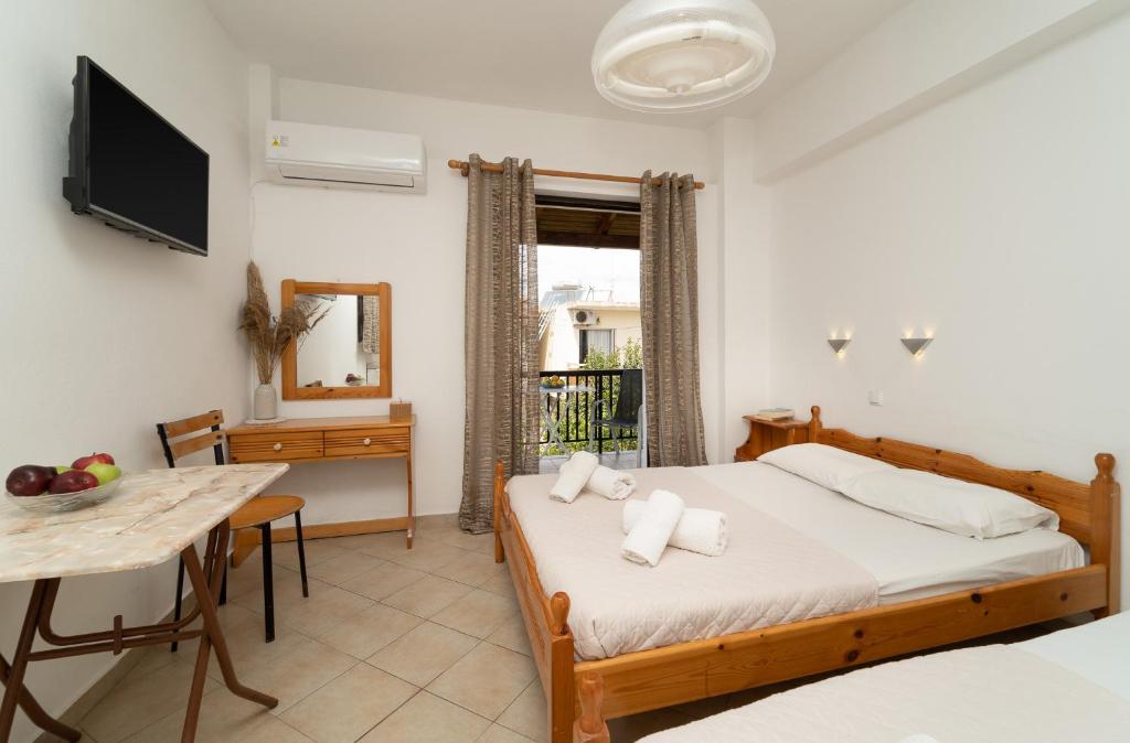 a bedroom with a bed and a table and a television at Tsimiklis Apartments in Finikounta