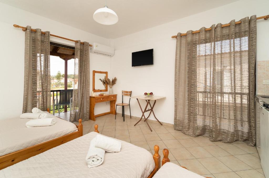 a bedroom with two beds and a table and a window at Tsimiklis Apartments in Finikounta