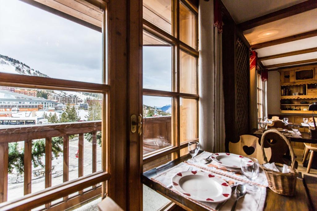 a dining room with a table and a window at Les Monts Charvin in Courchevel