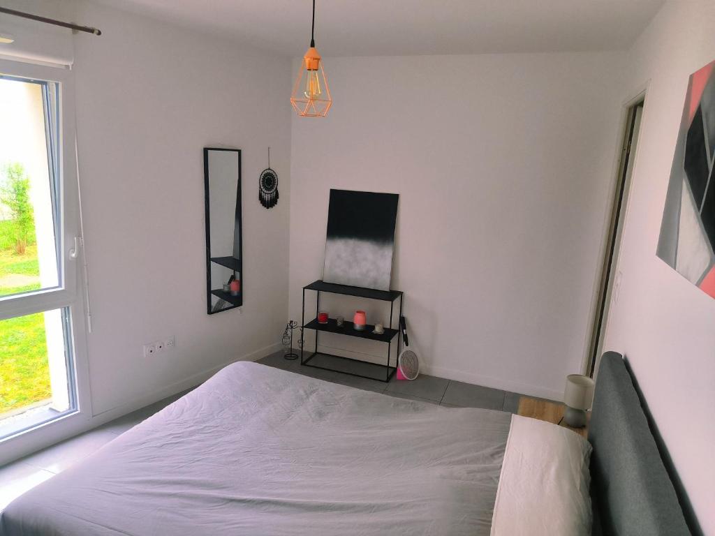 a white bedroom with a bed and a window at Superbe appartement avec jardin in Courrejean