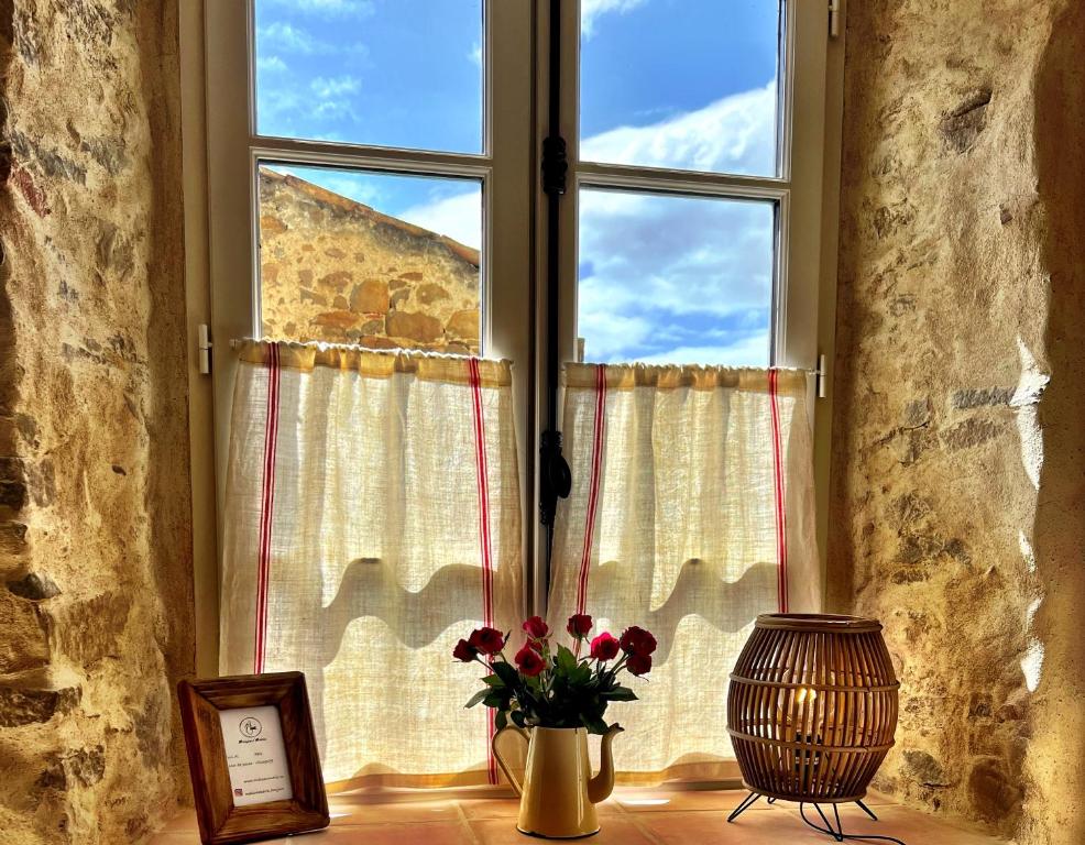 a window with a vase of flowers and a picture at Maison Marie in Lagarde