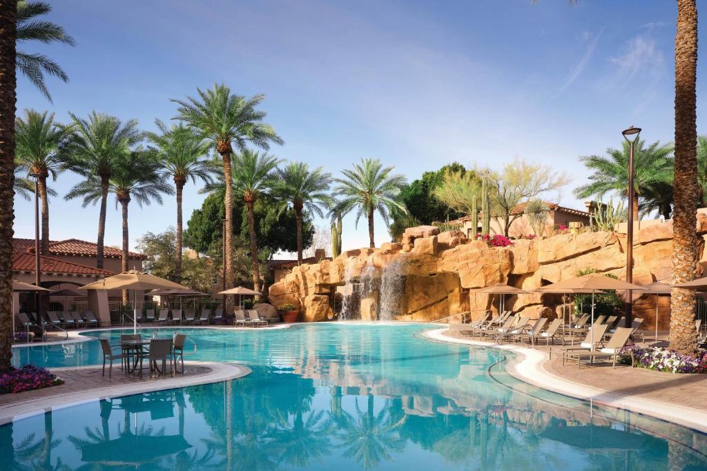 einen Pool in einem Resort mit einem Wasserfall und Palmen in der Unterkunft Sheraton Desert Oasis Villas, Scottsdale in Scottsdale