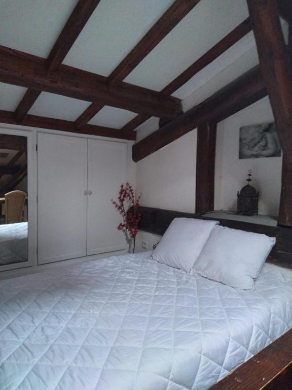 Cette chambre dispose d'un grand lit blanc et de plafonds en bois. dans l'établissement Centre Sète, à Sète