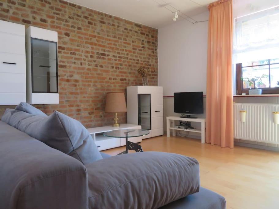 a living room with a couch and a brick wall at Landhausstil trifft Moderne in Muhlheim am Main