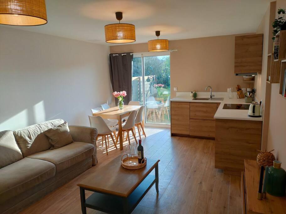 a living room with a couch and a table and a kitchen at La Closerie de Thimécourt in Luzarches