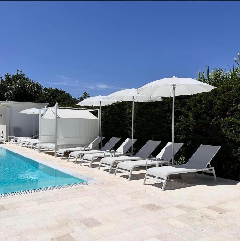 a row of lounge chairs and umbrellas next to a pool at Il Leone Di Mare in Procida