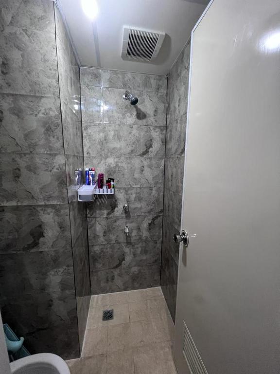 een badkamer met een douche en een glazen deur bij Apartemen Serpong Greenview Premium in Ciater-hilir