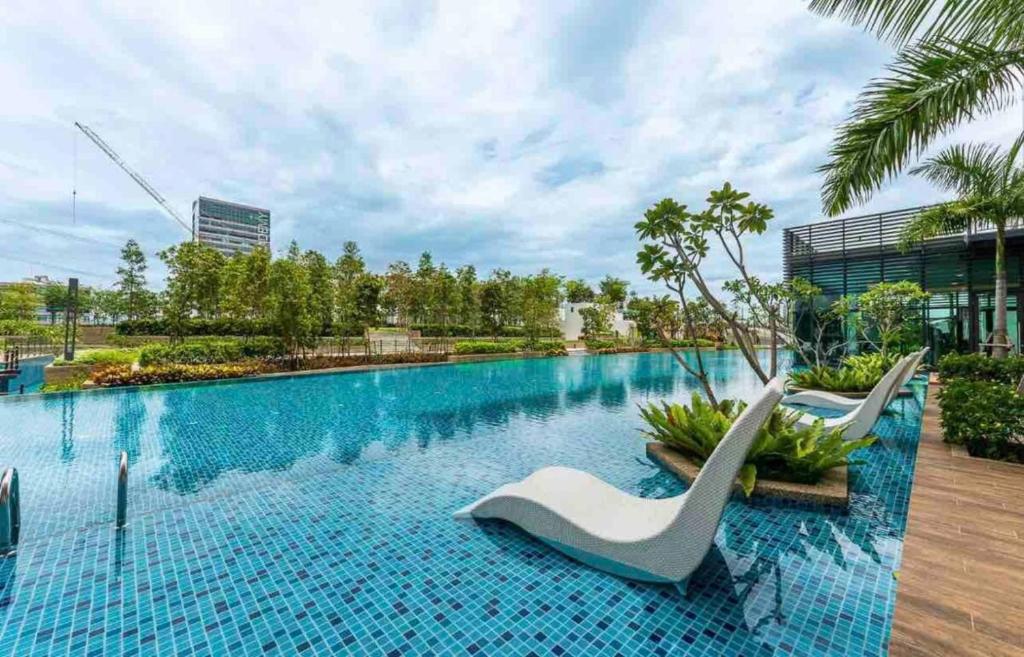 a large swimming pool with two white chairs in front of a building at Greenfield Residence Bandar Sunway in Petaling Jaya