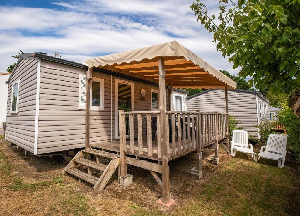 dom z werandą z 2 krzesłami i parasolem w obiekcie Camping Les Moutiers-en-Retz w mieście Prigny