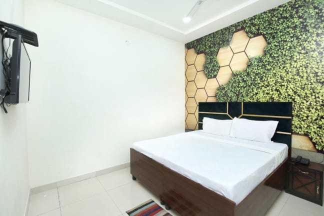 een slaapkamer met een bed met een schilderij aan de muur bij OYO Hotel Golden Crown in Rājpura