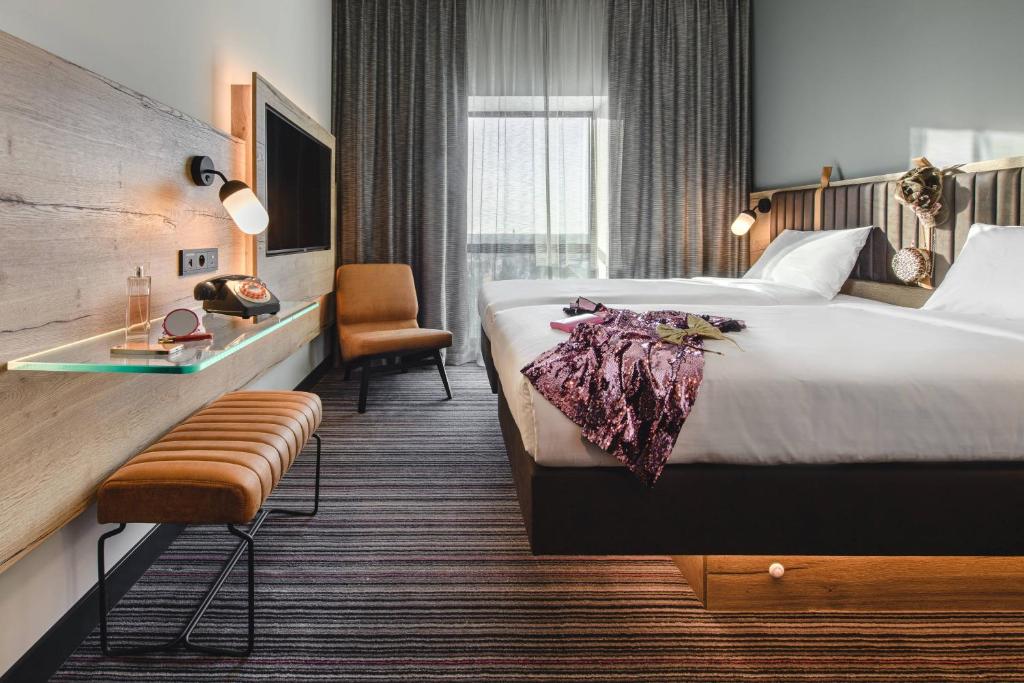 ein Hotelzimmer mit einem großen Bett und einem Stuhl in der Unterkunft Moxy Poznań Airport in Posen