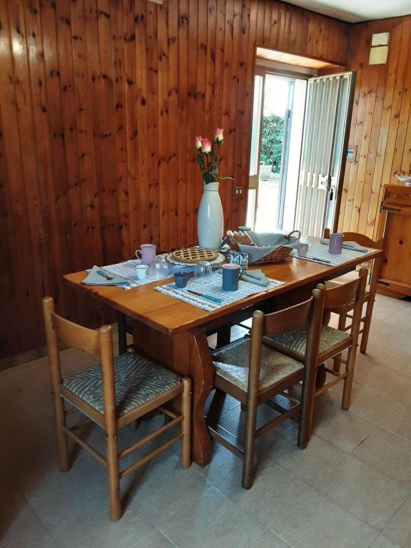 una mesa de madera con sillas y un jarrón con flores en La Cascina di Fox en Terni