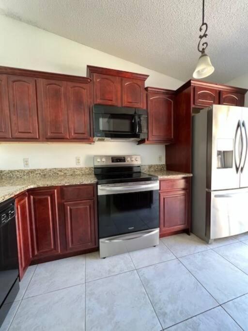 uma cozinha com armários de madeira, um fogão e um frigorífico em The Modern Bloom em Orlando