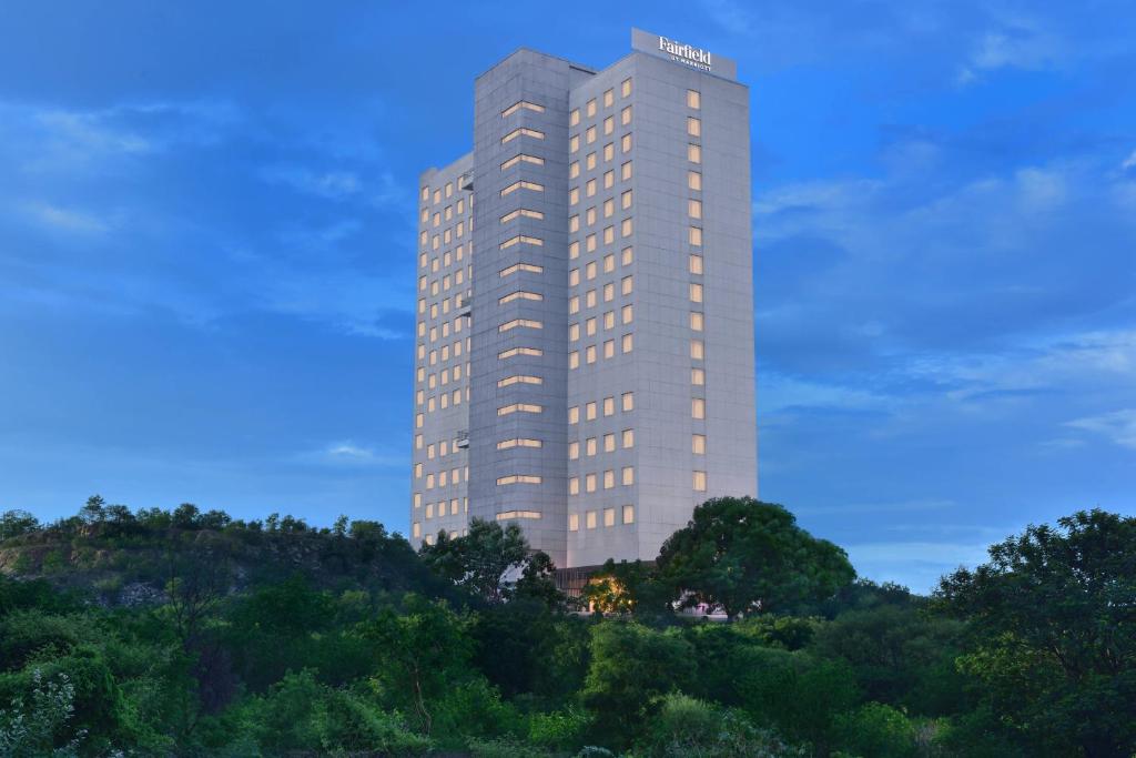 a tall building on top of a hill with trees at Fairfield by Marriott Hyderabad Gachibowli in Hyderabad
