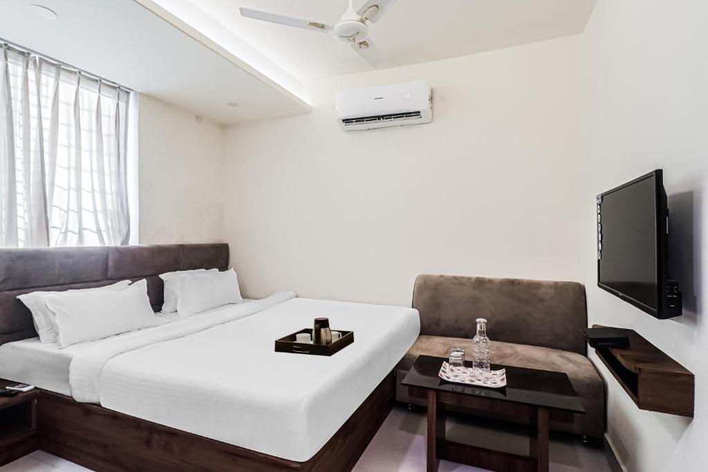 a bedroom with a bed and a couch and a tv at Super Townhouse 83601 Hotel Marina in Rānchī