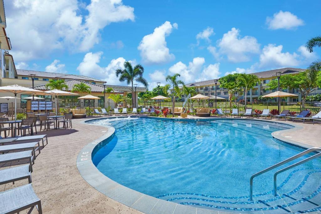 a swimming pool at a resort with chairs and umbrellas at Residence Inn by Marriott Oahu Kapolei in Kapolei