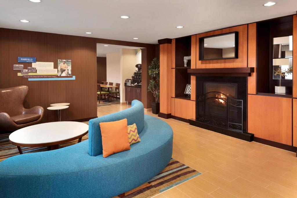 Fairfield Inn & Suites Minneapolis Bloomington/Mall of America في بلومنغتون: غرفة معيشة مع أريكة زرقاء ومدفأة