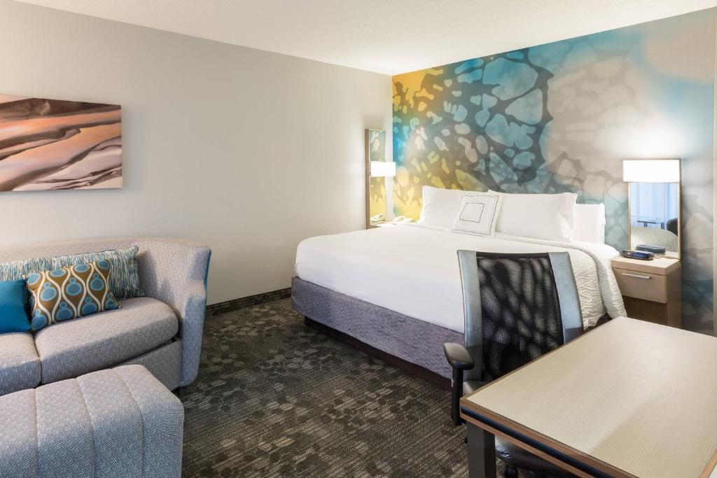 a hotel room with a bed and a couch at Courtyard Dallas Mesquite in Mesquite