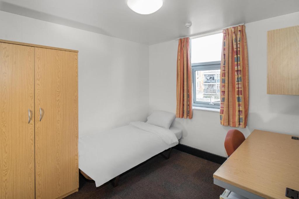 a small room with a bed and a window at Davies Court (Canary Wharf) in London